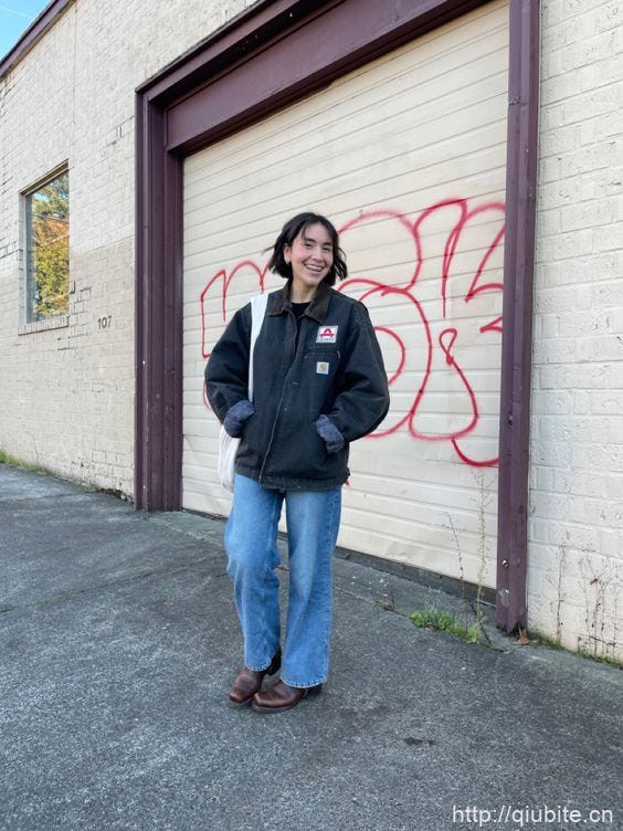 a man standing in front of a building with graffiti on it 搭配裤装,复古工装夹克的“出厂CP”