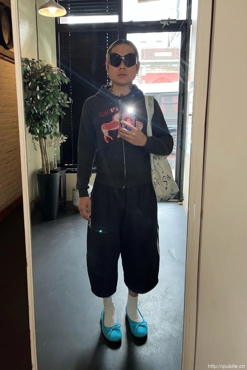 a person wearing sunglasses and holding a cell phone 为什么2024年了,芭蕾平底鞋还在流行?